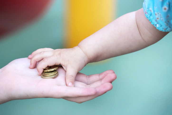 Child grabbing coins from adult's hand