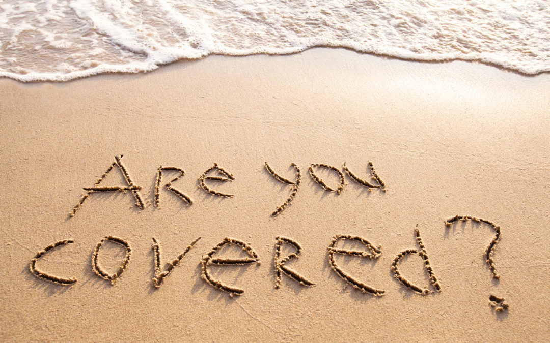 are you covered, travel insurance concept, text on sandy beach